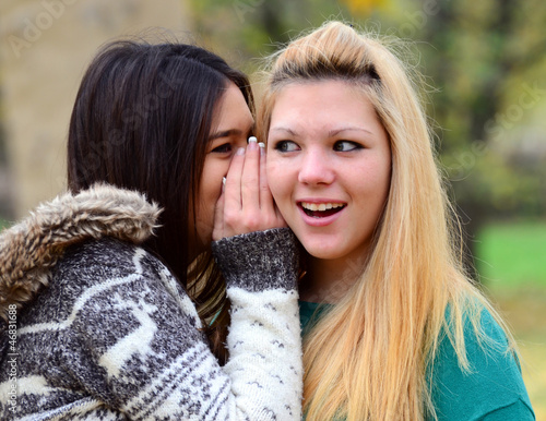 Two teen girls whispering rumours