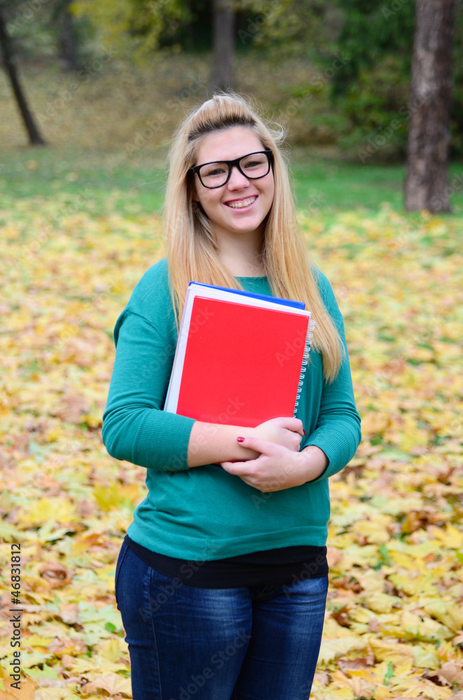 Obraz premium Portrait of smiling student girl holding books