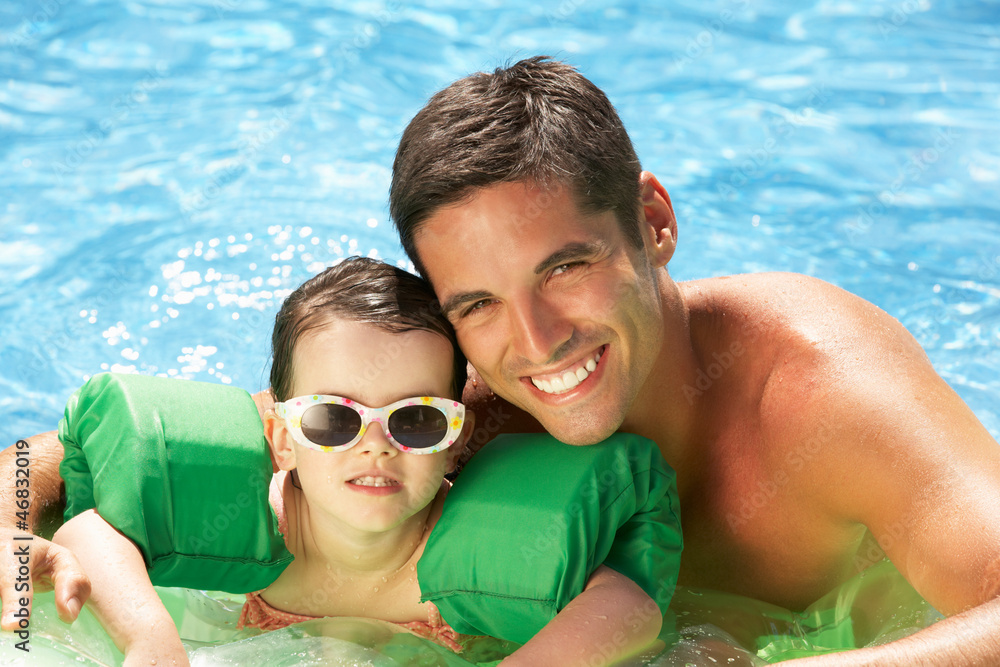 Father And Daughter With Armbands In Swimming Pool