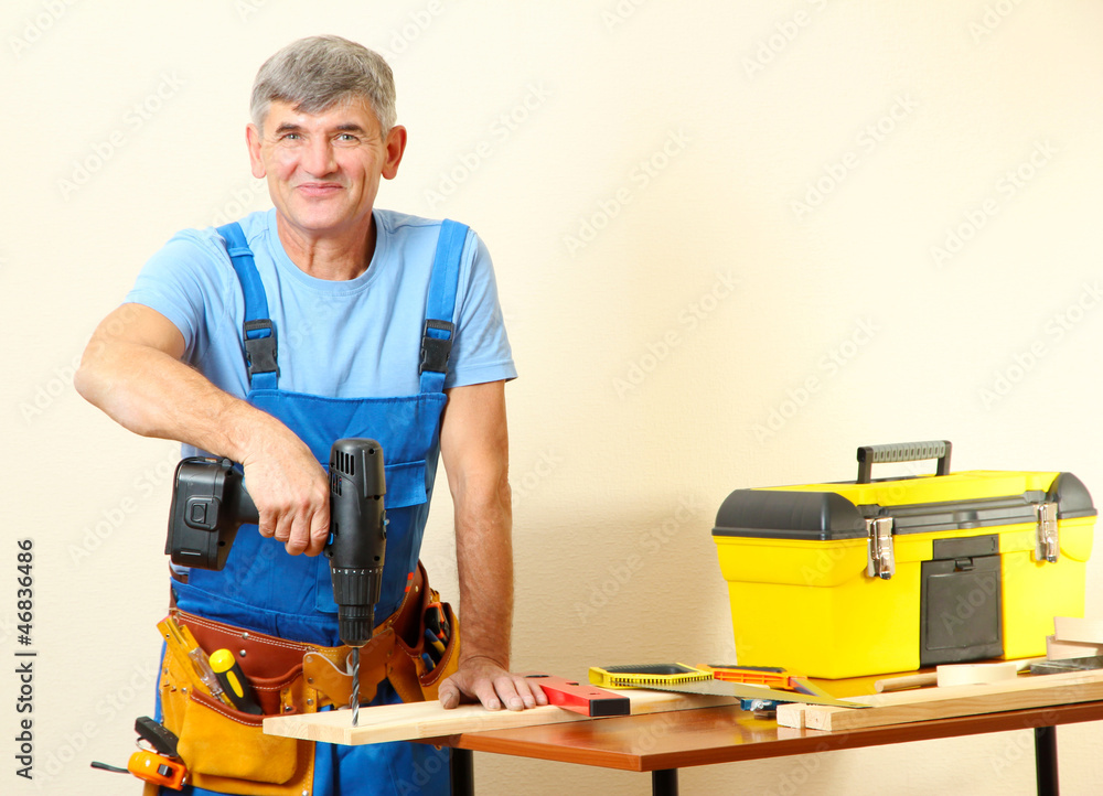 Builder drills board on table on wall background Builder drills board on table on wall background
