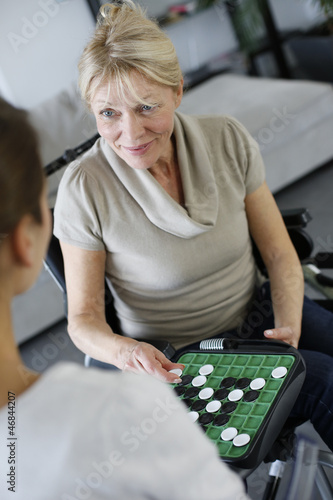 Young homecarer playing game with elderly woman photo