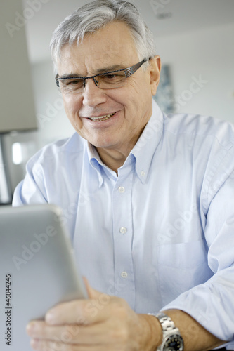 Senior businessman working on digital tablet from home