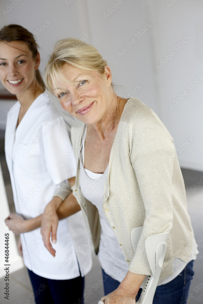 Nurse helping old woman to walk with crutches Nurse helping old woman to walk with crutches