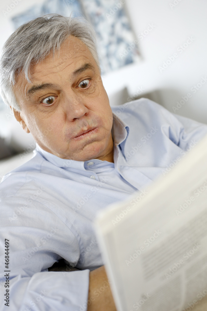 Senior man reading newspaper with puzzled look Senior man reading newspaper with puzzled look