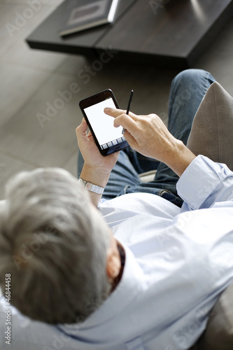 Back view of senior man using smartphone