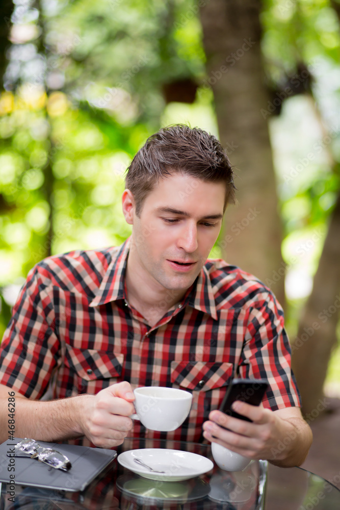 Business man sitting at table in cafe using mobile phone