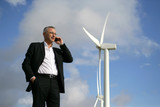 Man on mobile phone next to wind turbine