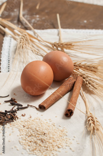 Two Egg, spices, wheat on light tablecloth and wooden table photo