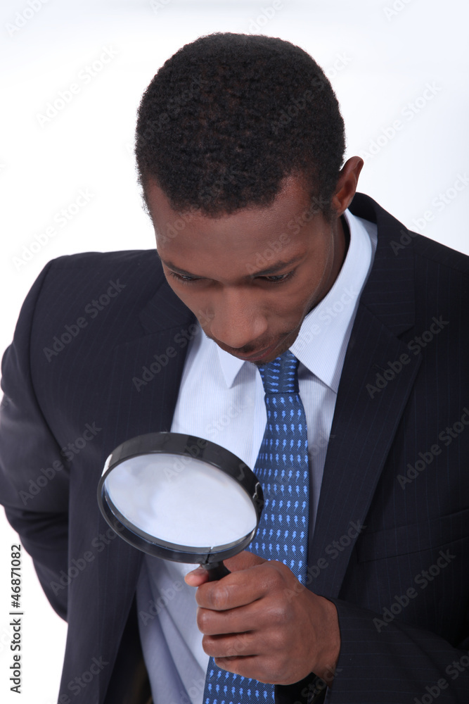 Curious man inspecting an object with a magnifying glass Curious man inspecting an object with a magnifying glass