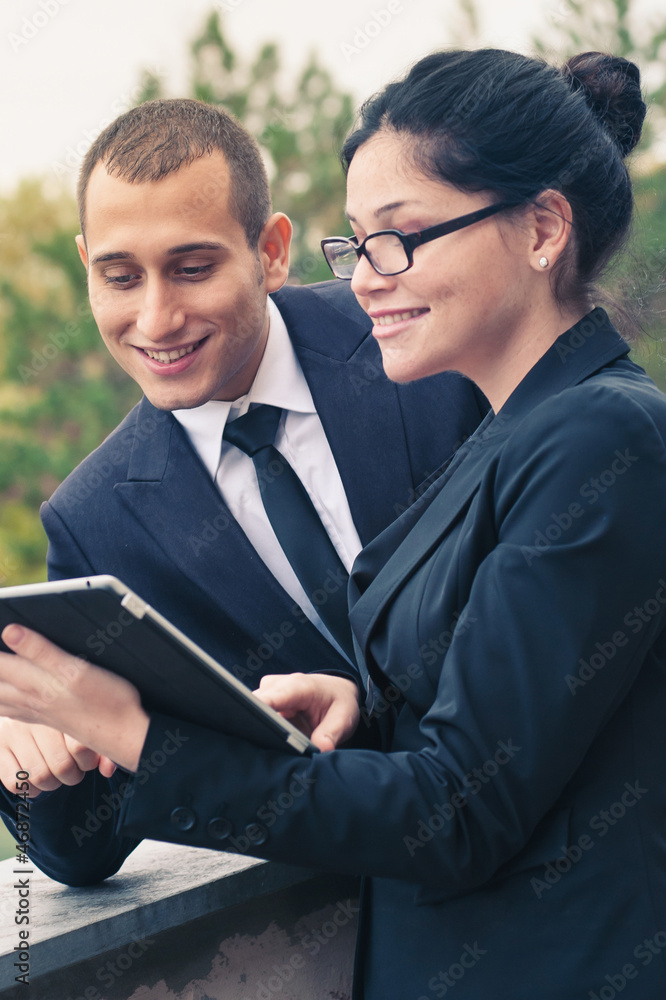 Couple of businessman and woman looking at tablet outdoors. Couple of businessman and woman looking at tablet outdoors.