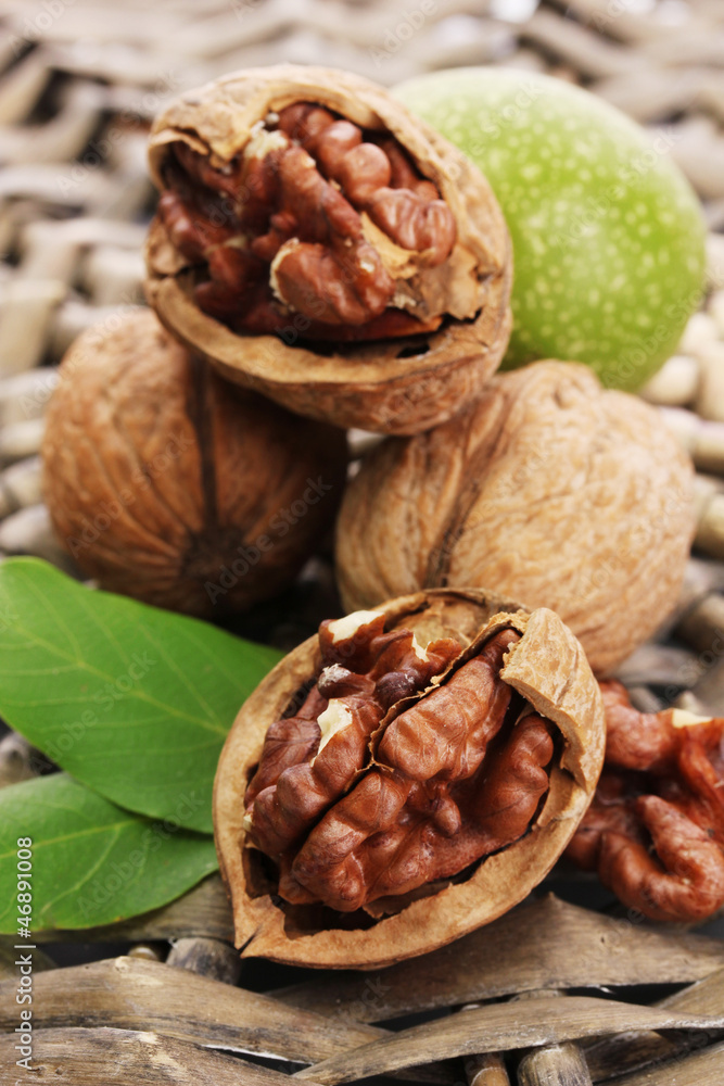 walnuts with green leaves, on wicker background walnuts with green leaves, on wicker background