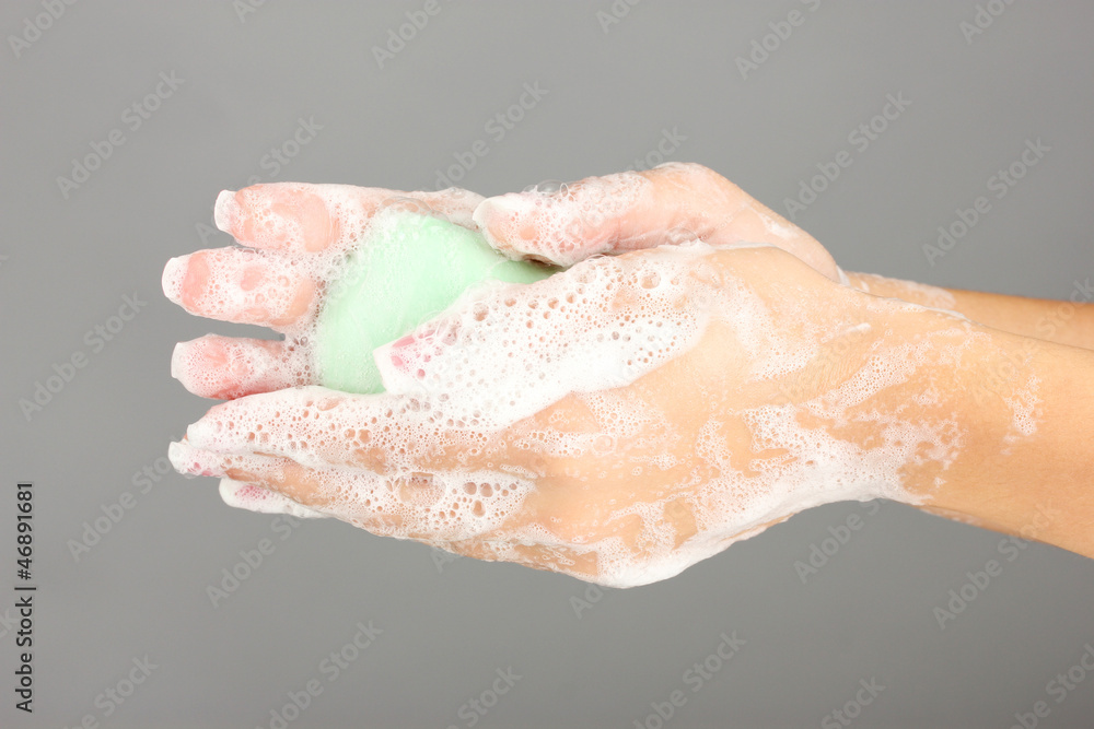 Woman's hands in soapsuds, on gray background close-up Woman's hands in soapsuds, on gray background close-up