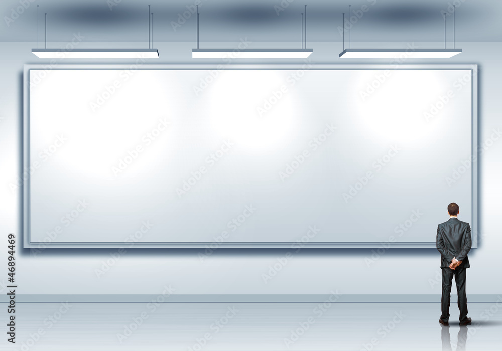 Business person standing near a blank billboard Business person standing near a blank billboard