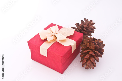 Christmas gift box and pine cones over white background. © samsam62