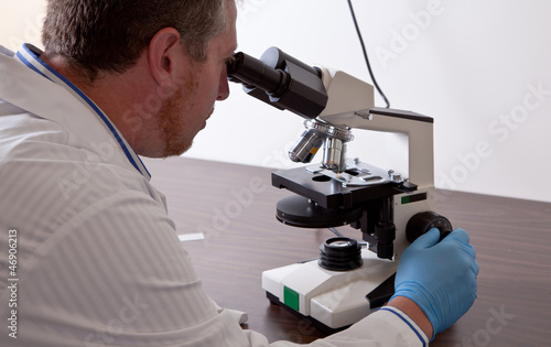Fotografie Lab scientist looks into microscope
