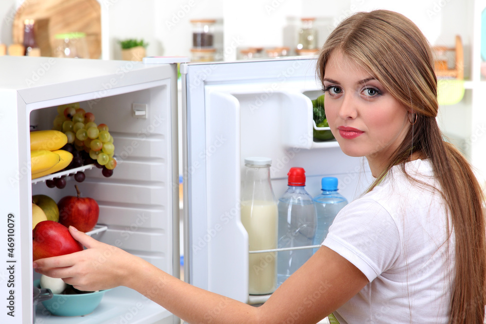 Young girl near refrigerator in kitchen