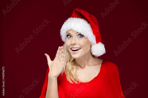 Woman in Christmas cap covers her mouth with hand