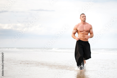 Billede på lærred Physically fit man running on the beach
