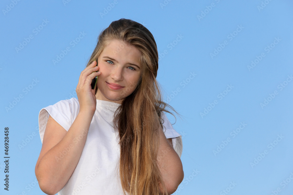 Smiling girl with mobile phone stand at background of blue sky. Smiling girl with mobile phone stand at background of blue sky.