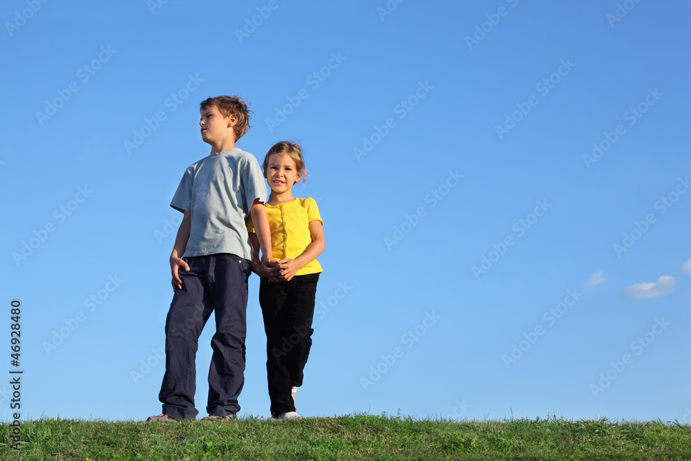 Boy and girl stand together on green grass at background of sky. Boy and girl stand together on green grass at background of sky.
