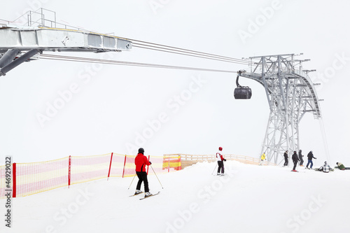 Big funicular in mountains. Skiers and snowboarders ride in Alps