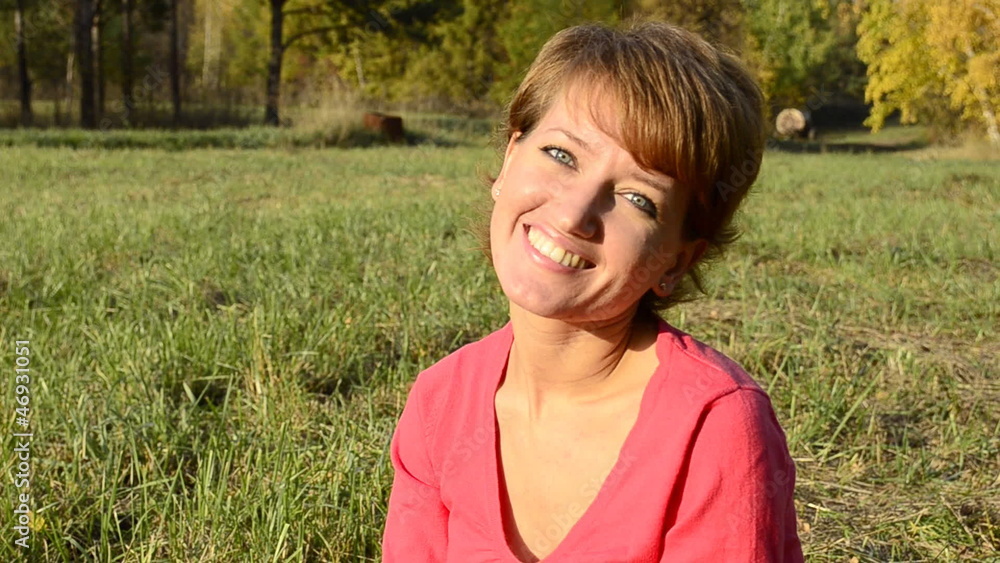 A young woman in a red sweater smiling sitting in autumn park A young woman in a red sweater smiling sitting in autumn park