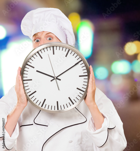 female chef hiding behind a clock