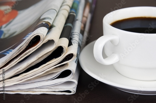 Take a break: pile of newspapers and cup of coffee on the table