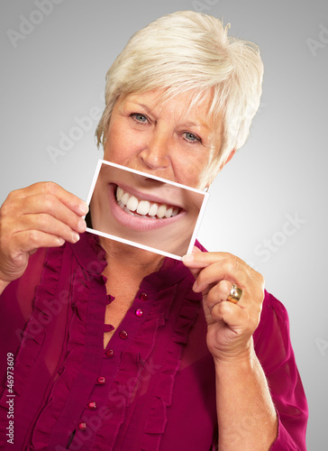 Senior Woman With Manifying Glass Showing Teeth photo