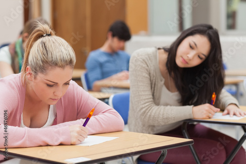 Brunette is trying to copy blonde student in exam