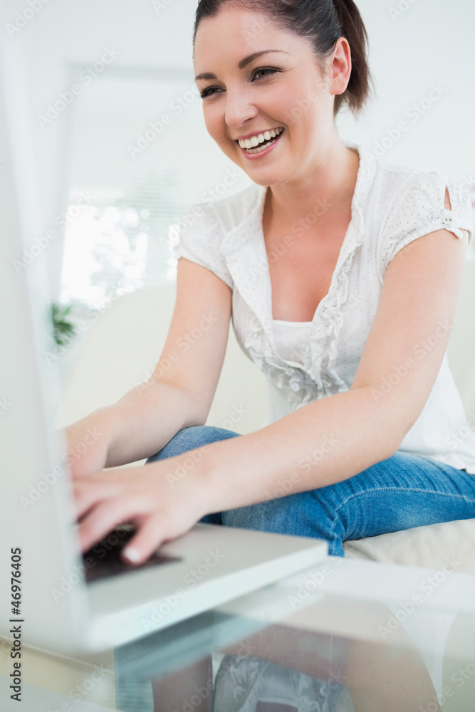 Laughing woman on the couch using a laptop Laughing woman on the couch using a laptop