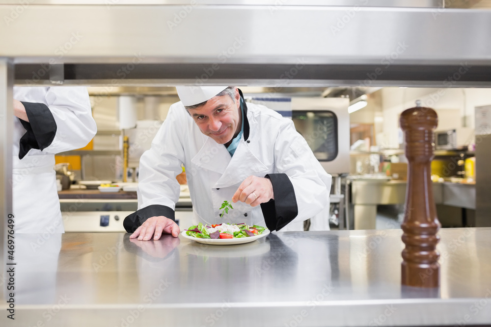 Smiling chef garnishing salad Smiling chef garnishing salad