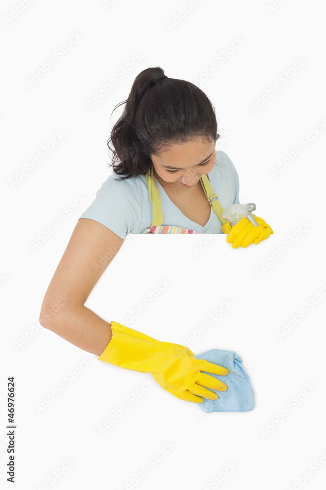 Smiling woman in gloves cleaning white surface Smiling woman in gloves cleaning white surface