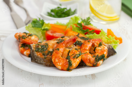 fish with shrimps and salad on the plate and glass of water