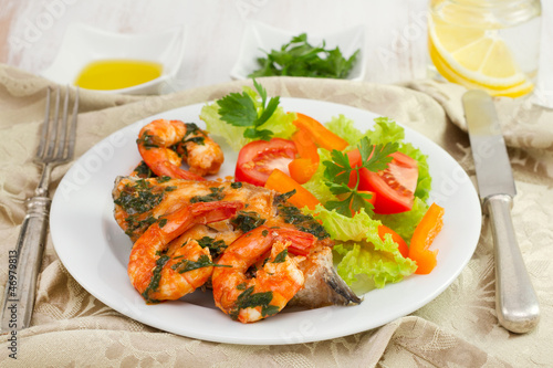 fish with shrimps and salad on the white plate and water