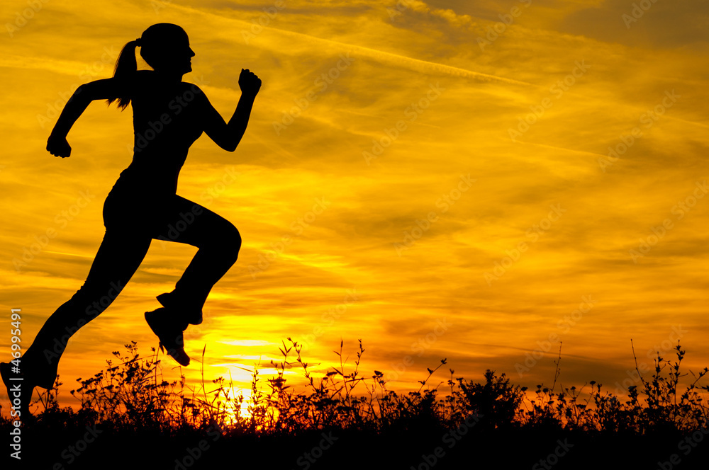 Silhouette of young sports woman running in the summer nature at sunrise
