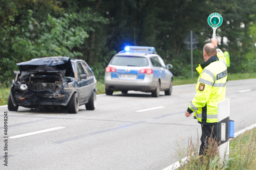 Polizist an Unfallstelle mit grüner Kelle Polizist an Unfallstelle mit grüner Kelle