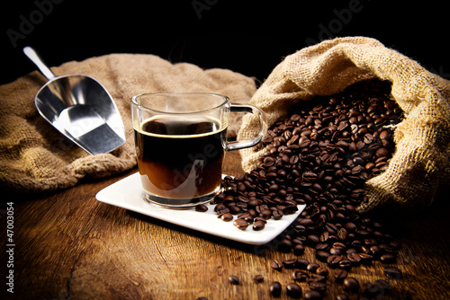 Kaffeetasse und geröstete Bohnen auf Holztisch - Kaffeegenuss