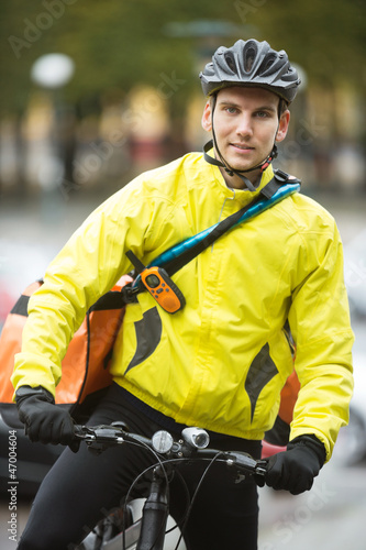Young Male Cyclist With Courier Delivery Bag On Street