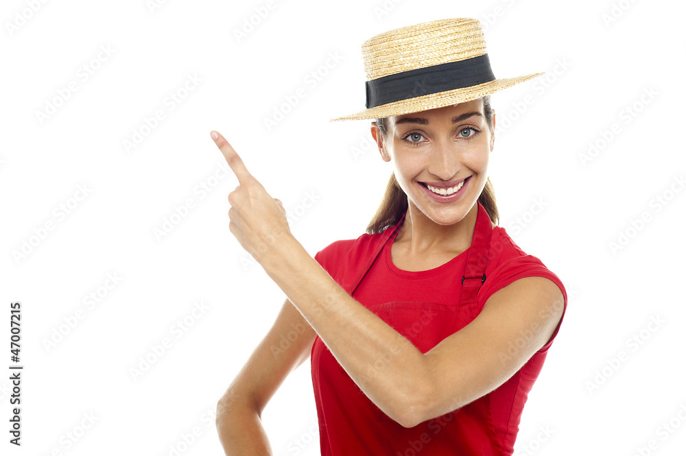 Smiling woman wearing straw bowler hat pointing away Smiling woman wearing straw bowler hat pointing away
