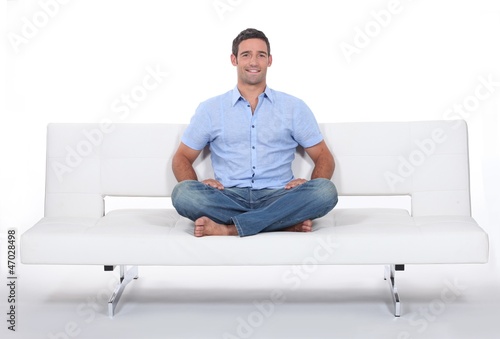 Young man sitting on white sofa