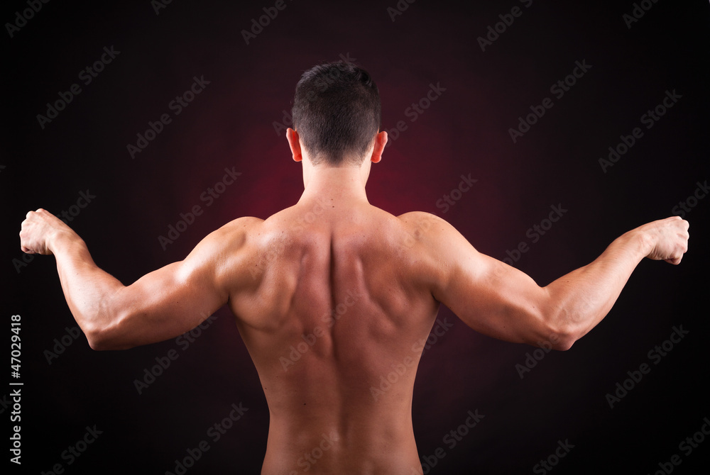 Muscular young man from back on black background Muscular young man from back on black background