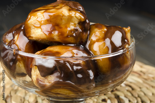 Profiteroles with chocolate sauce and syrup in a glass bowl. photo