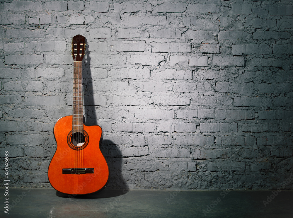 Acoustic guitar leaning on grungy wall