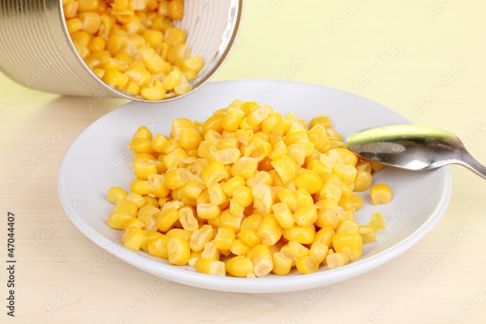 Open tin can and plate with corn and spoon Open tin can and plate with corn and spoon