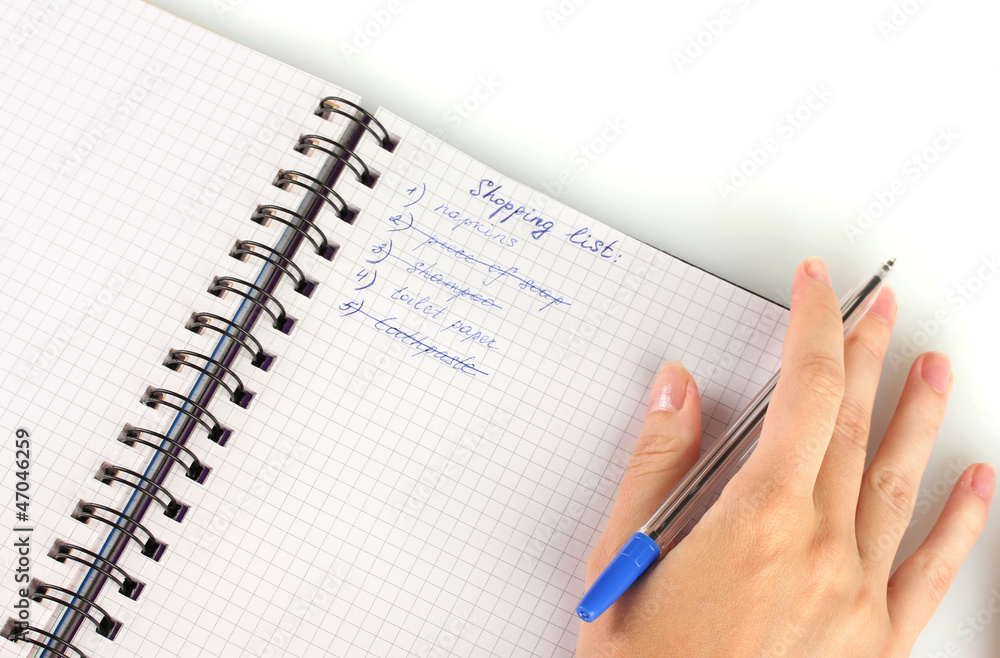 woman's hand holding a notebook with a shopping list close-up woman's hand holding a notebook with a shopping list close-up