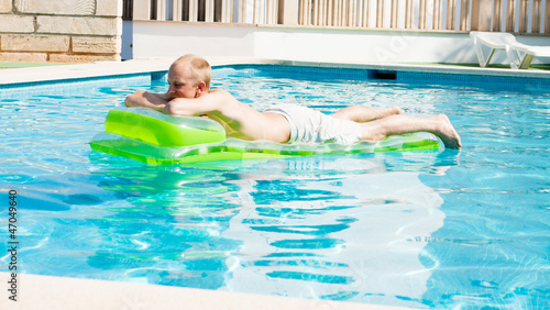 Junger mann auf einer grünen luftmatratze in einem schwimmbad © juniart