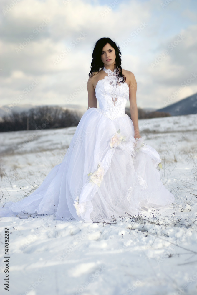 pretty young woman posing in wedding dress  on winter snow
