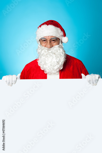 Aged Santa standing behind a blank ad board © stockyimages