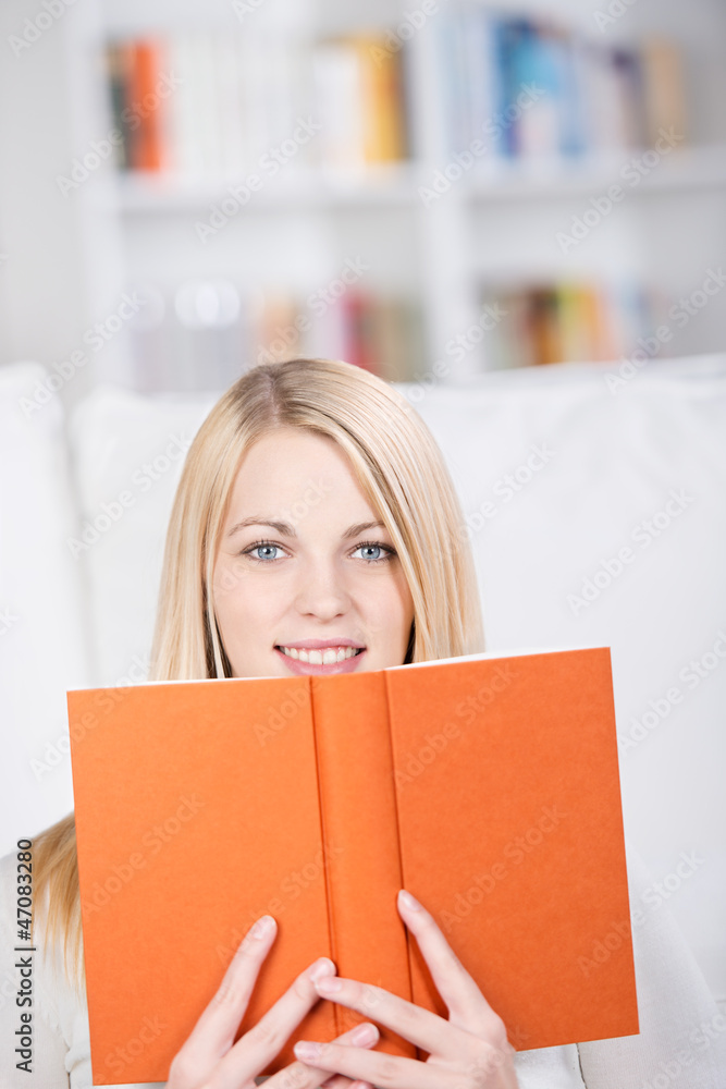 blonde frau schaut über ihr buch blonde frau schaut über ihr buch